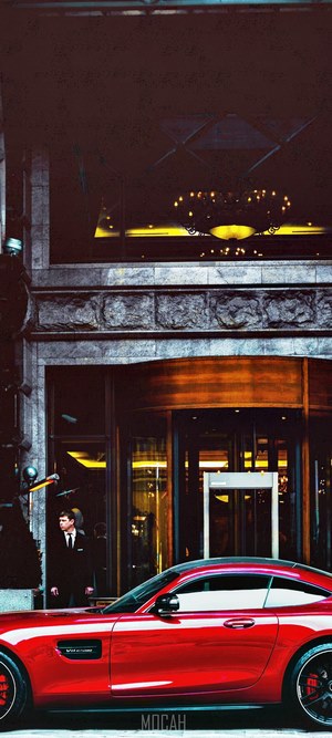 Man in suit and red sports car outside building