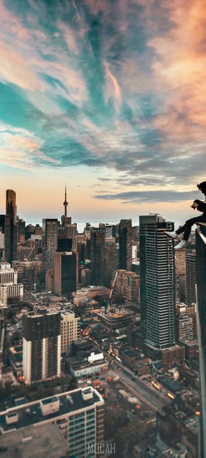 Person sitting on skyscraper edge overlooking Toronto skyline