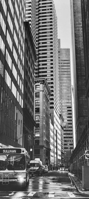 Black and white street scene with tall buildings and a bus