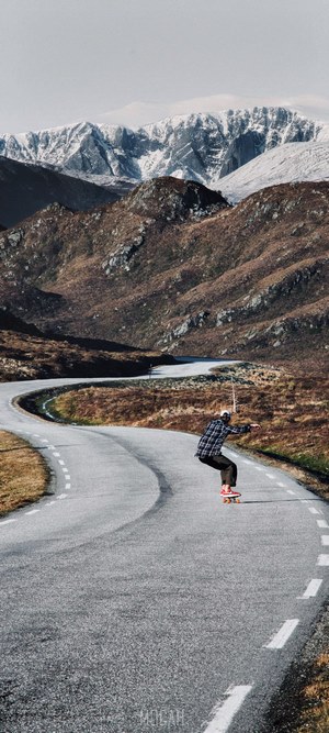 Skateboarder on a winding road in Norway mountains