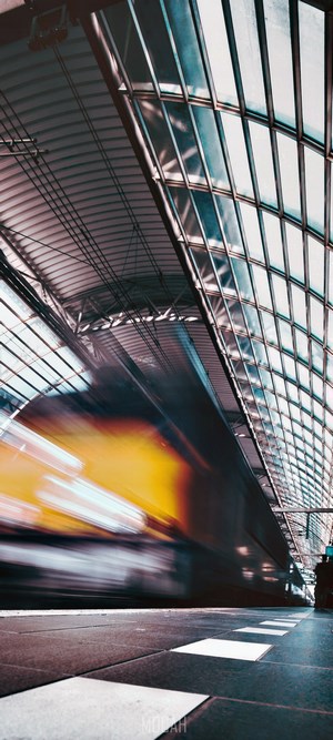 Train speeding through a modern train station with glass roof