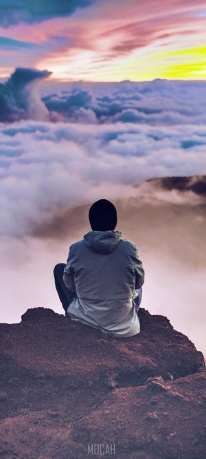 Person watching sunset over clouds from mountain
