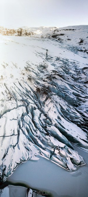 Aerial view of a vast glacier with icy formations and a frozen lake
