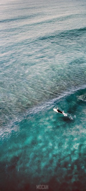 Surfer paddling out in turquoise ocean waves
