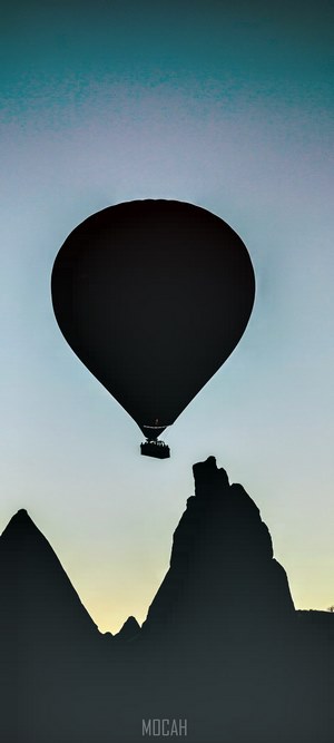 Hot air balloon silhouette over rock formations