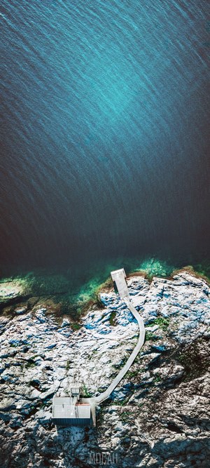 Aerial view of a pier and cabin on a rocky shore