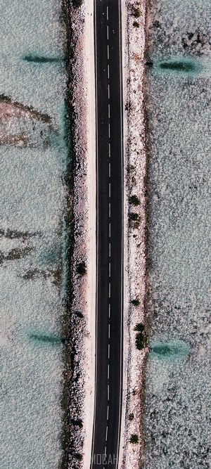 Aerial view of a road through shallow turquoise water