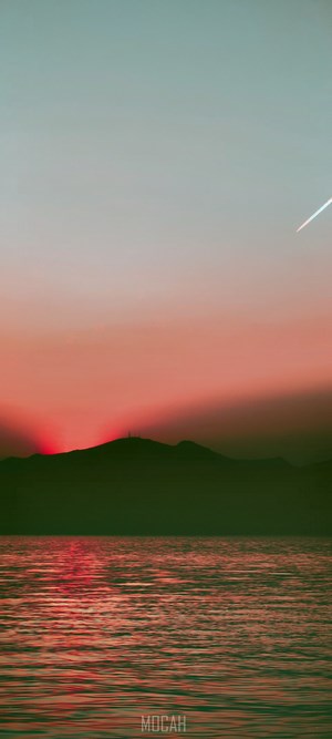 Sunset over the sea with mountain silhouette