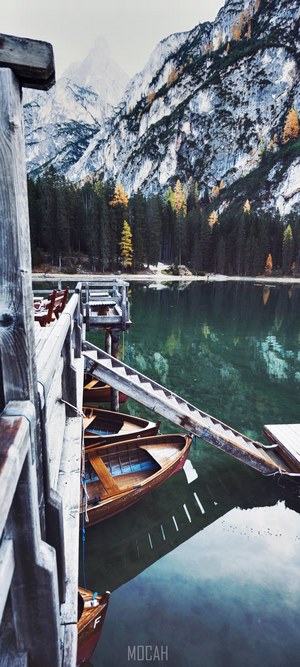 Wooden boats docked at a pier with mountains and forest