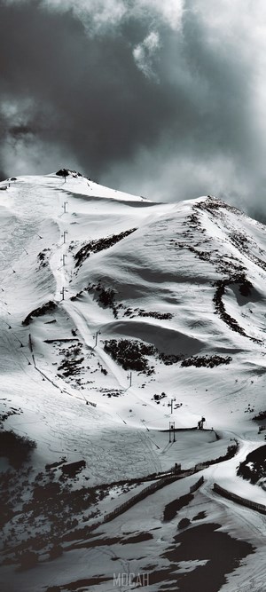 Snowy ski resort with ski lifts and cloudy sky