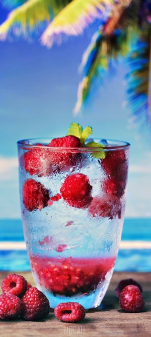 Raspberry drink with ice and mint on a beach background