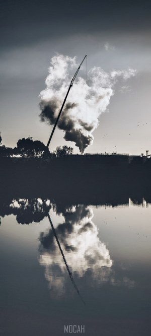 Smoke from industrial chimney reflected in water