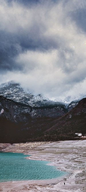 Turquoise lake and snow-capped mountains under cloudy sky
