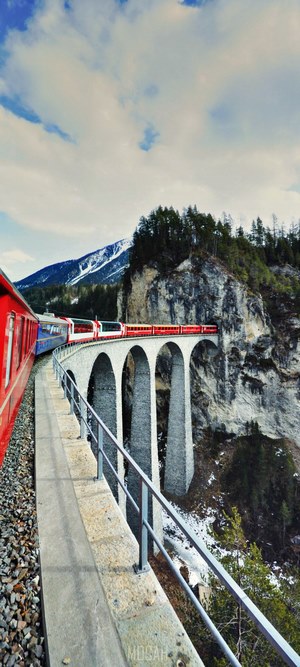 Red train on a viaduct bridge in the mountains