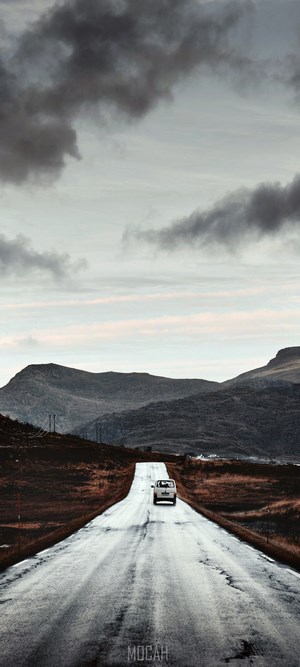 White car on a wet road in a mountainous landscape