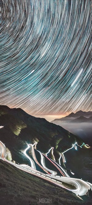Star trails over winding mountain highway at night