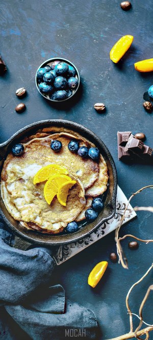 Pancakes with blueberries and orange slices in a cast iron skillet