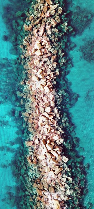 Breakwater made of rocks in turquoise water