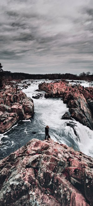 Person standing on rocks overlooking rapids