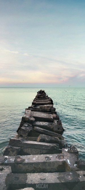 Stone pier extending into the ocean at sunset