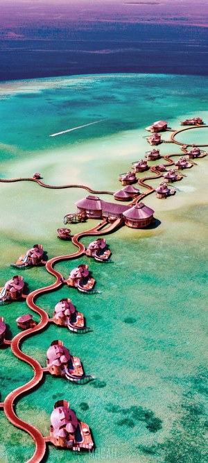 Aerial view of overwater bungalows in turquoise water