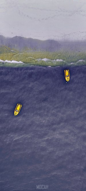 Two yellow jet skis on the water near a beach