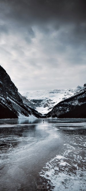 Frozen Lake Louise with Mountains and a Lone Figure