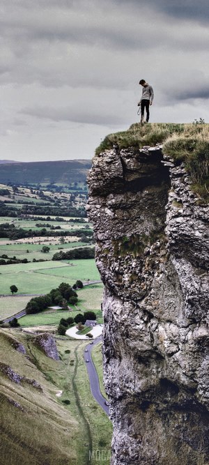 Man standing on a cliff edge overlooking a valley