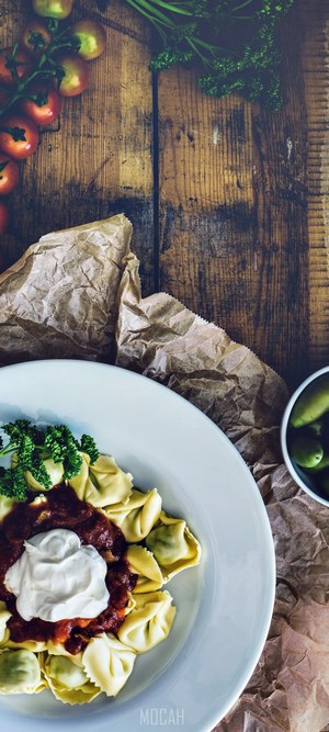 Tortelloni with tomato sauce and sour cream on a plate