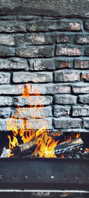 Fireplace with burning logs and brick wall