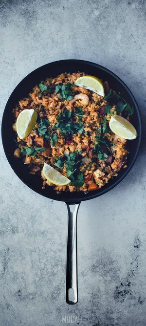 Paella in a pan with lime and cilantro