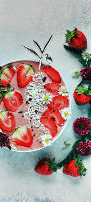 Strawberry smoothie bowl with coconut and flowers