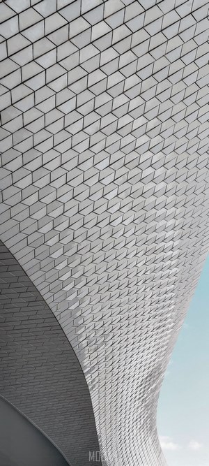 Curving white tiled facade against pale blue sky