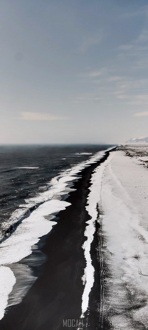 Black sand beach with snow and ocean waves
