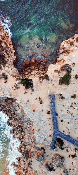 Aerial view of a wooden boardwalk along a rocky coastline