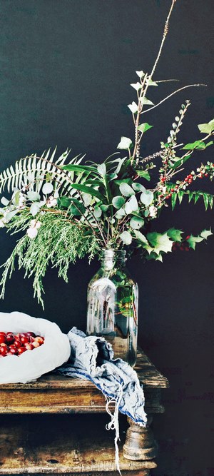 Holiday arrangement with berries and greenery in a vase