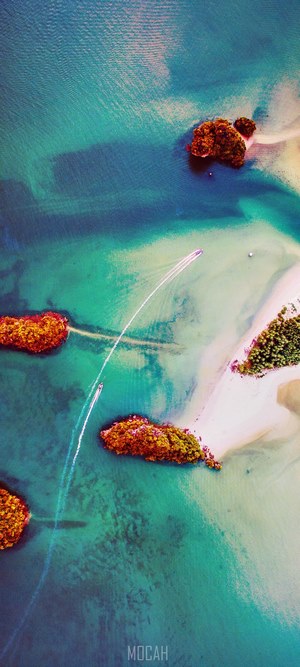 Aerial view of boats speeding between tropical islands