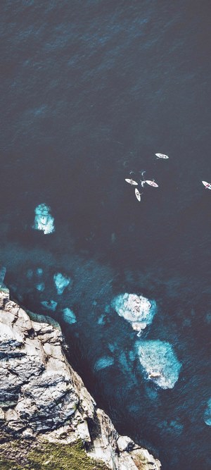 Kayaks on the ocean near rocky cliffs