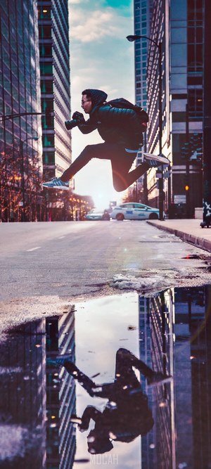 Man jumping in city street with reflection