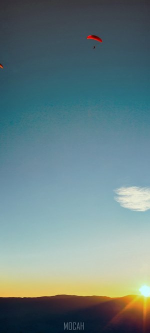 Paragliders over mountains at sunset