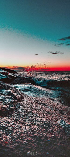 Sunset over ocean waves crashing on rocks