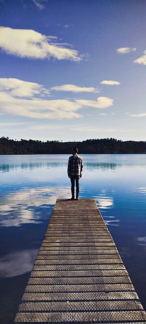 Man on dock overlooking a reflective lake