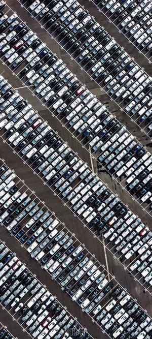 Aerial view of a large car parking lot with rows of cars