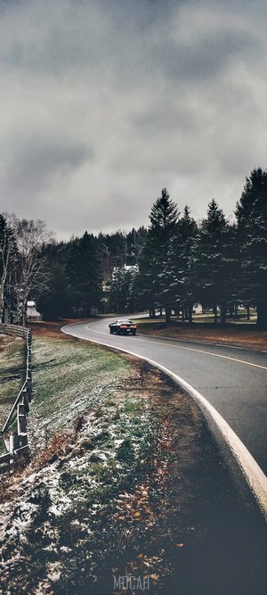 Car driving on a winding road with first snow