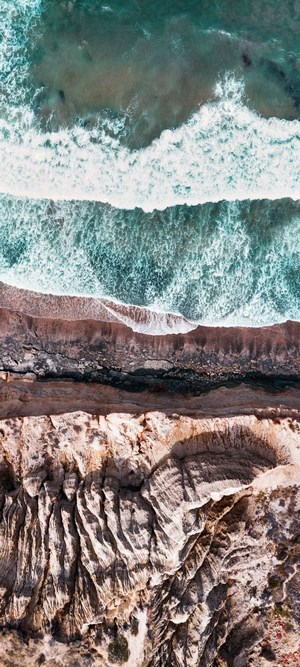 Aerial view of ocean waves crashing on a rocky coastline