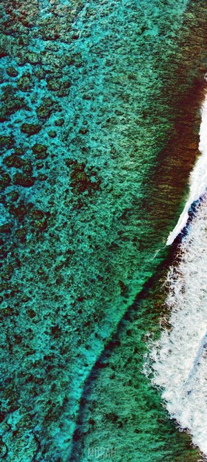 Aerial view of turquoise ocean water with coral reefs and waves