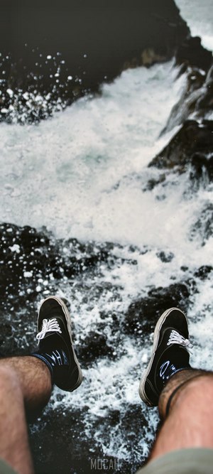 Person sitting by the ocean with Oppo Find X2 Neo