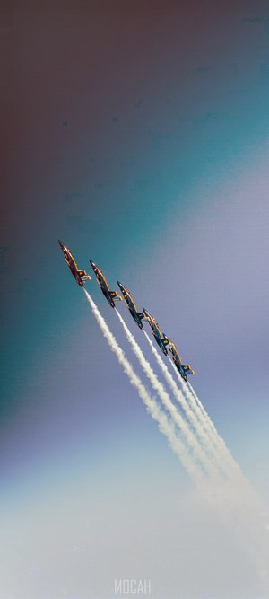 Five aerobatic airplanes in formation with smoke trails