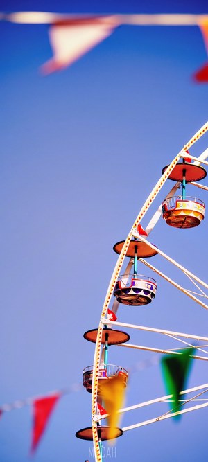 Ferris wheel with flags against a blue sky