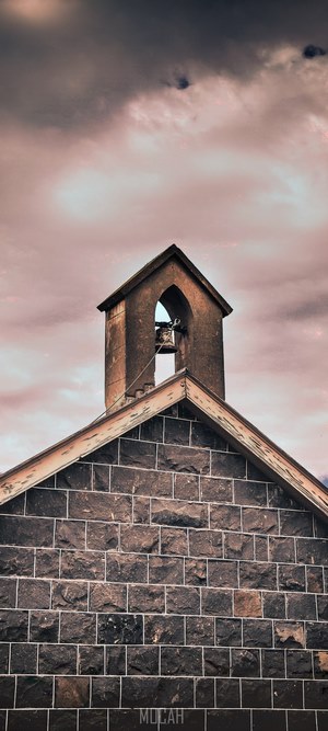 Bell tower on a stone building under a cloudy sky